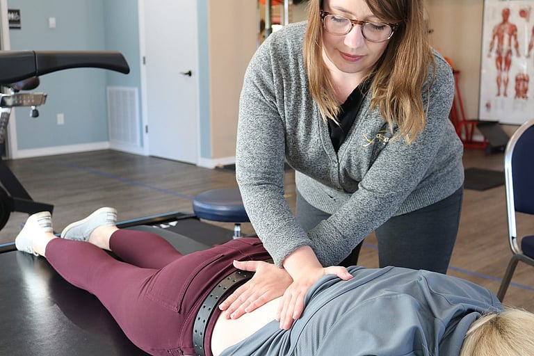 Therapist applying pressure to the patients low back to help relax muscles and manage pain at the Cody Advantage Rehab clinic
