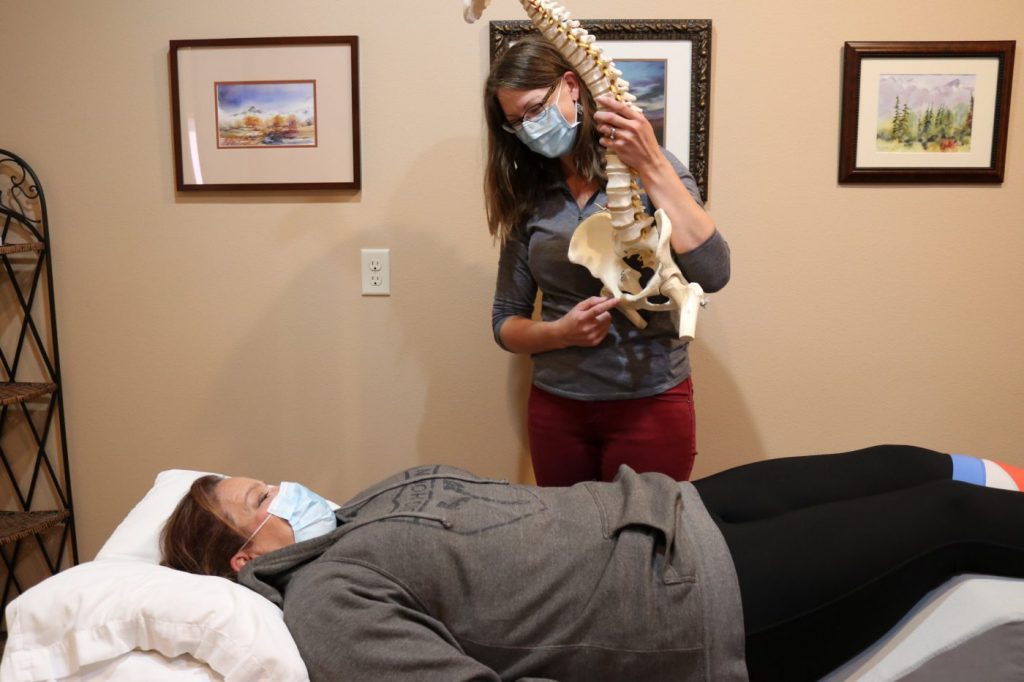 Physical therapist in Cody Wyoming showing pain location on a model of spine and bone structure