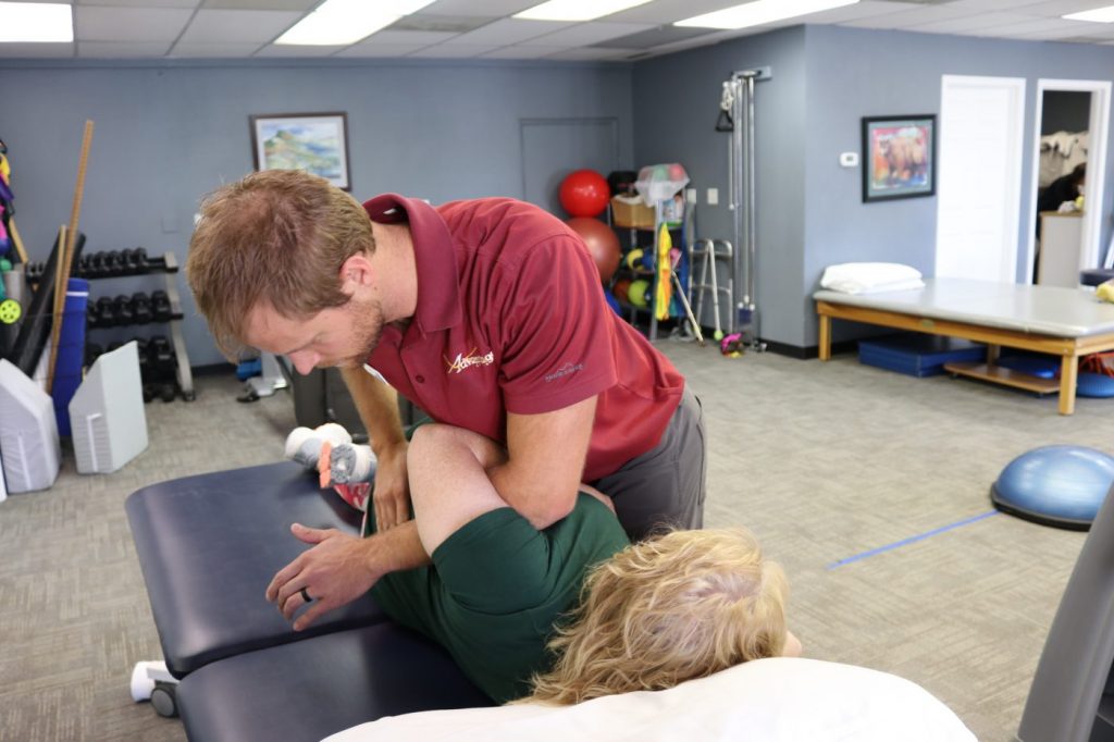 Advantage Rehab therapist in Powell Wyoming using body weight and manual therapy to manipulate the patients spine and release tention in the back and hip