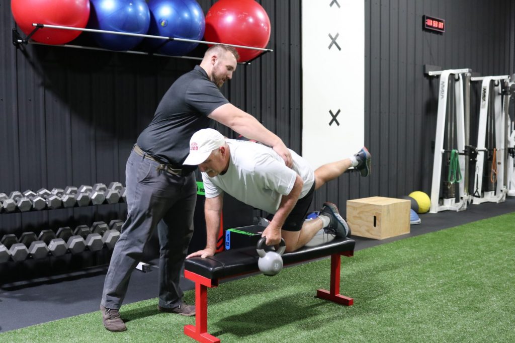 Core strength balance exercise with assisted cues from a personal trainer in Cody Wyoming