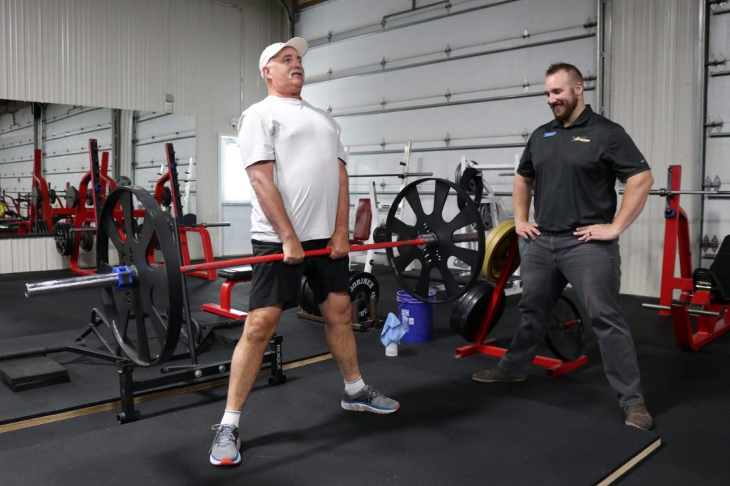 Hip and leg strengthening exercise monitored by a personal trainer at The Barbell Club in Cody Wyoming